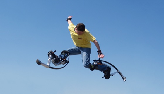 Una persona en el aire sobre zancos saltarines Skyrunner bajo un cielo azul despejado